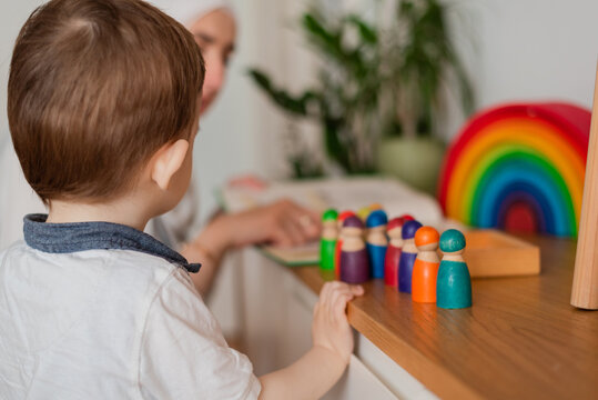 Teacher and preschool child playing together with colorful toys in the Montessori school classroom or kindergarten.