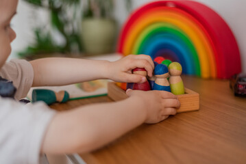 Close up hands of a Montessori kid playful learning arranging by engaged colorful wooden sensorial blocks educational toys cognitive creative skills.