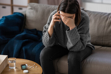 mental health, psychological help and depression concept - stressed woman with sedative medicine on table calling on phone at home