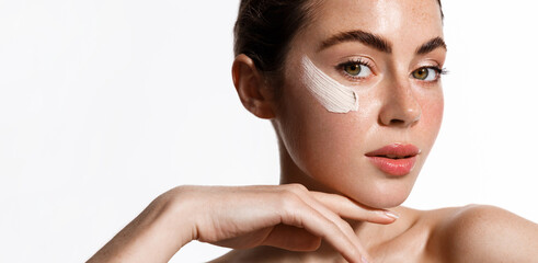 Face and makeup. Beautiful brunette woman with facial spa mask, cream or scrub on cheek, standing...