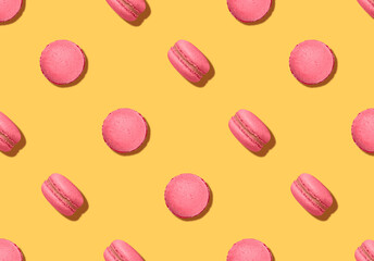 Pattern with almond cookies. Pink colored macaroons on bright yellow backdrop
