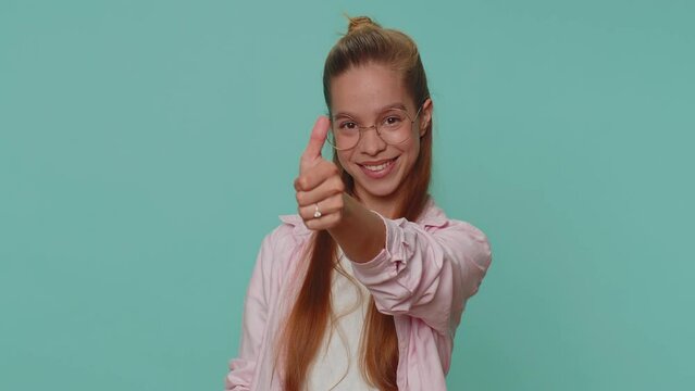 Lovely cheerful pretty teen girl greatly approves your suggestion, shaking head approvely, satisfied with good quality work, like proposal. Young stylish child kid on blue studio background indoors
