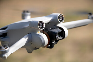 Close up drone with camera sensors and props flying in air with nature behind - DJI Mini 3 Pro aerial uav