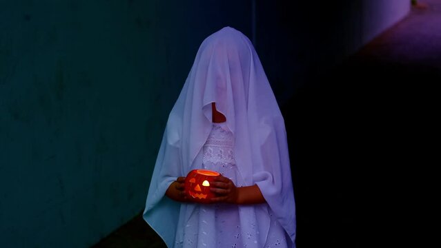 ghost girl in white hoodie holds pumpkin candle in her hands in creepy house, sad child ghost at night, halloween festival concept, frightening mystical events, friday the 13th, horror movie scene