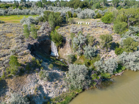 Waterfall drone aerial picture in Wyoming with green trees with water falling into Shoshone river with bumble bee boxes in background