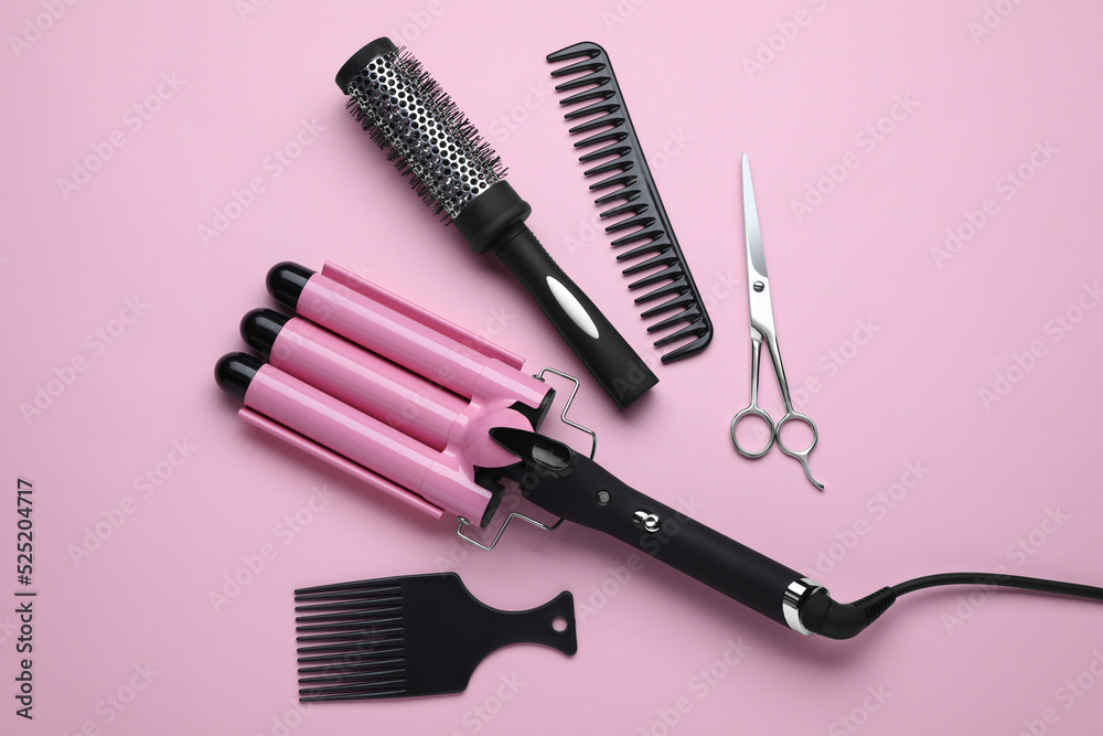 Wall mural Flat lay composition of professional hairdresser tools on pink background