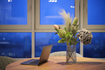 Laptop with flowers in a vase on the table