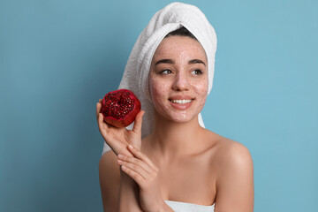 Woman with pomegranate face mask and fresh fruit on light blue background