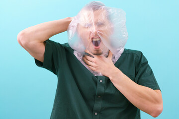 A man suffocating because of a plastic bag on his head on a blue background. Ecology. Package....