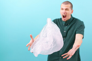 Naklejka premium A surprised man with an open mouth holding his hands above a flying plastic bag on a blue background. Free. Faces. Future. Disagree. Gesture. Bad. Rude. Surprised. Plastic Bags. Wondering. Amazed