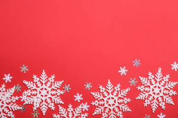 Beautiful decorative snowflakes on red background, flat lay. Space for text