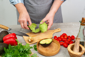 cook preparing avocado for serving. various vegetables and spices on the kitchen table.Close up.