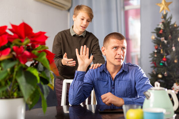 Middle age adult father making stop gesture to his son at home during Christmas weekend