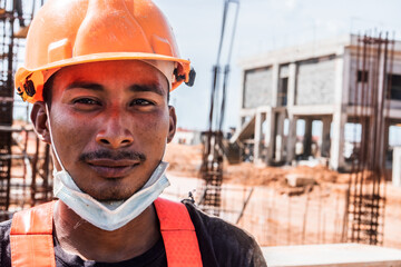 Latino indigenous blue collar worker in the construction of a work looking at the camera