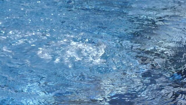 Ripple clear transparent water background in swimming pool. Blue and white tiles background. Hot tub of water used for hydrotherapy, relaxation or pleasure. Powerful jets for massage. Spas or jacuzzi