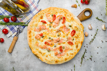 Pizza with salmon and anchovies with tomatoes on grey table top view