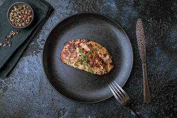Grilled chicken Breasts on black plate on dark stone table top view