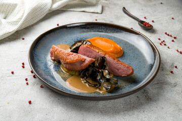 Duck breast with black mushrooms and mashed pumpkin on plate