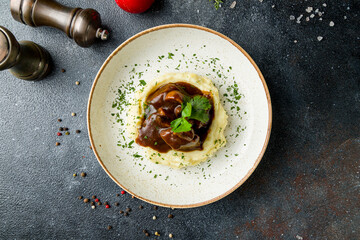 Beef cheeks with mashed potatoes and demiglass sauce on dark stone table top view - obrazy, fototapety, plakaty