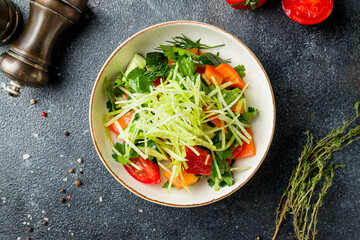 Vegetable salad with tomatoes and cucumbers on dark table top view