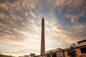 Selective blur on Broken Red brick chimney from an abandoned factory at dusk, with sun, dating back...