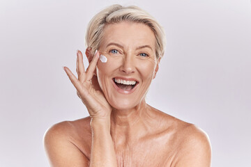 Skin, skincare or collagen lotion with old woman posing with a smile with her cosmetics and...