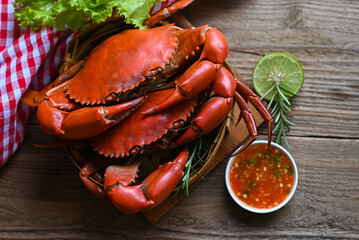 fresh crab on wooden and seafood sauce, seafood plate with herbs spices rosemary lemon lime salad lettuce vegetable, crab cooking food boiled or steamed crab red in the restaurant