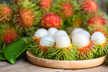 Fresh and ripe rambutan sweet tropical fruit peeled rambutan with leaf on wooden plate, rambutan fruit harvest from the garden rambutan tree