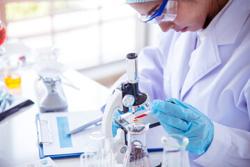 Asian Woman scientist hand write note research in medical lab look at science microscope medical test. Researcher biology chemistry. Asian Female technician laboratory using microscope blood test