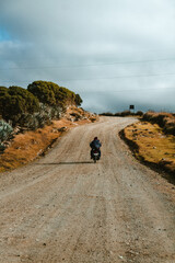 biker in the middle of dirt road with cold weather in warm tones
