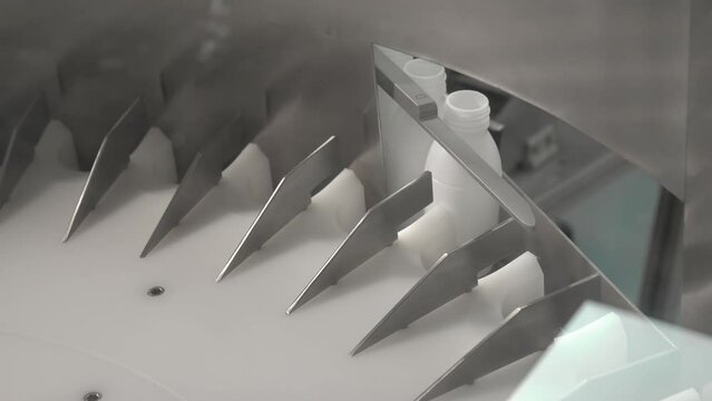 bottle feeding machine arranges white Mobilak bottles - close up shot