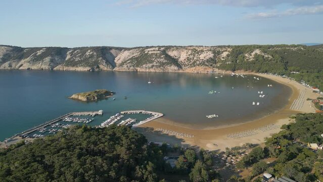 Aerial view of Lopar Croatia travel holiday destination with little port for luxury yacht and lonely remote solitary sandy beach, drone reveal seascape with hilly cliff