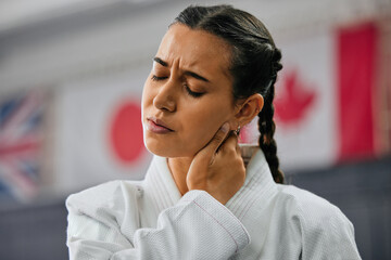 Woman karate student with bad neck pain at fitness training studio, person holding head from sport injury at health gym and muscle cramp from learning self defense at school. Painful joint accident