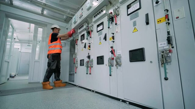 Electrical engineer working check the electric current voltage and overload at front of load center cabinet or consumer unit for maintenance in main power distribution system room.