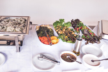 a buffet table with a white tablecloth and three salad bowls.