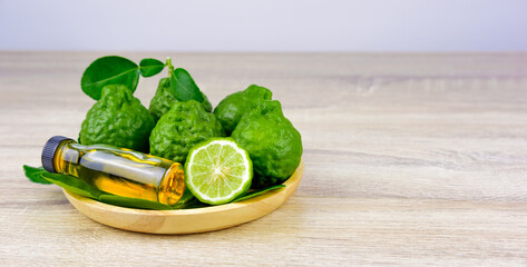 Fresh bergamot fruit And leaf with aromatic oil bottle on wood plate. For use in concept Thai herbs And essential oil for relaxation and air freshener.