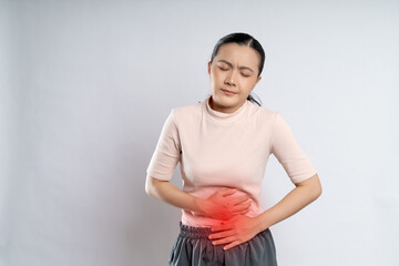 Asian woman was sick with stomach ache putting her hands on belly with red spot.