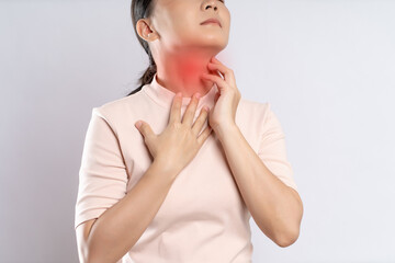 Asian woman was sick with sore throat and touching neck with red spot, standing isolated on white background.