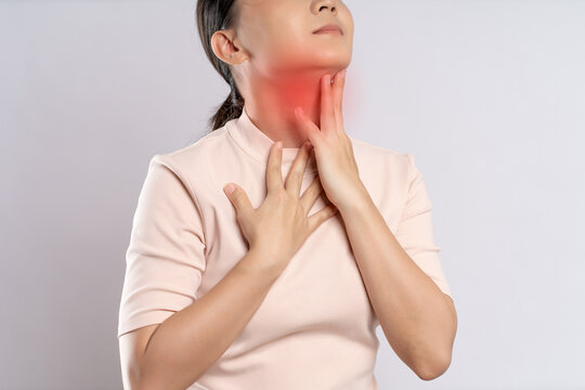 Asian woman was sick with sore throat and touching neck with red spot, standing isolated on white background.