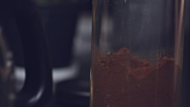Woman uses a spoon to scoop fresh coffee grounds for morning coffee. Extreme close up shot.