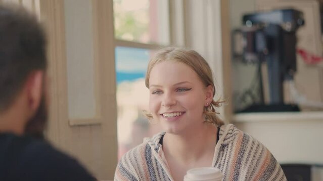 Girl smiling in a positive conversation with a guy in a bright cafe. Slow motion.