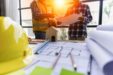 Engineers and architects discuss new projects on the construction site. With blueprints and using a...