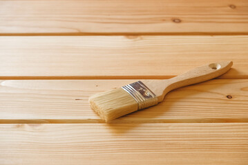Paint brush with bristles and a wooden handle on background natural boards