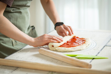 The chef is coocing a sweet roll with berry jam on a silicone baking mat.