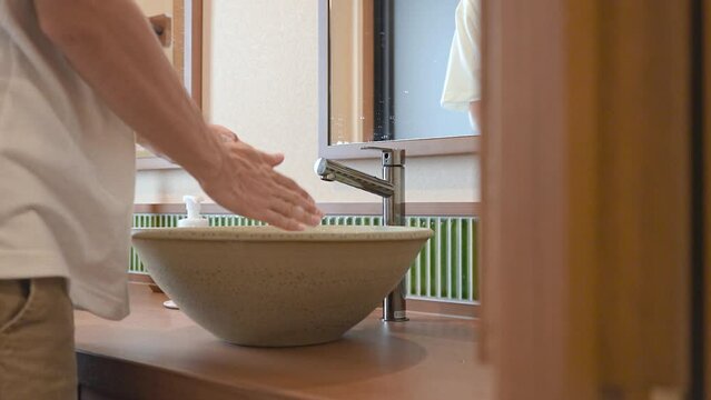 おしゃれな洗面所で手を洗う30代の男性