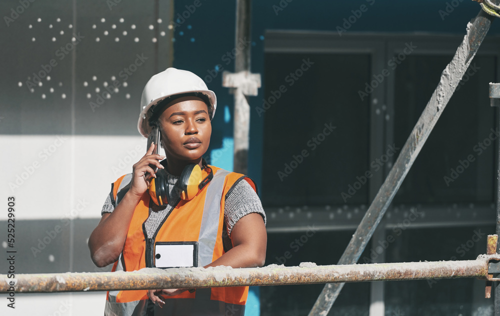 Canvas Prints Construction worker talking on a phone call while standing in a building site. Professional builder discussing plans and strategy, checking the inside structure. Civil engineer doing a safety check