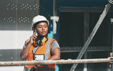 Construction worker talking on a phone call while standing in a building site. Professional builder...