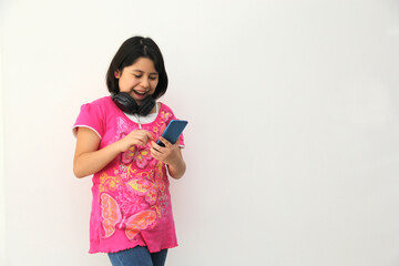 10-year-old Hispanic girl listens to music on her headphones connected to her cell phone dances, sings and enjoys the rhythm happy and excited

