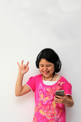 Obraz na płótnie Canvas 10-year-old Hispanic girl listens to music on her headphones connected to her cell phone dances, sings and enjoys the rhythm happy and excited 