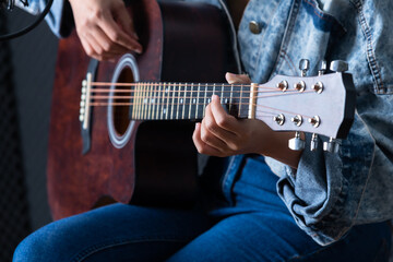 Close-up woman fingers holding mediator with a Guitar recording a song in recording studio